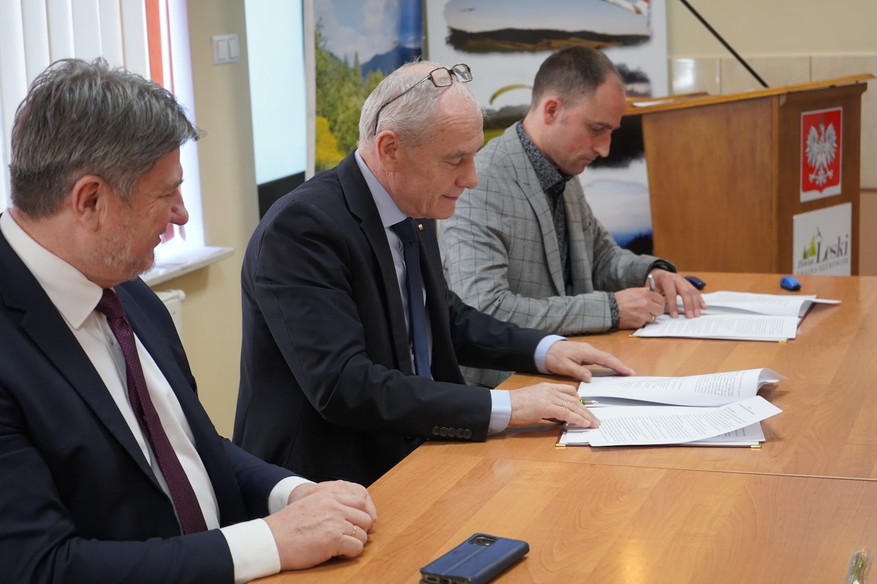 Obraz przedstawia proces podpisywania umowy.